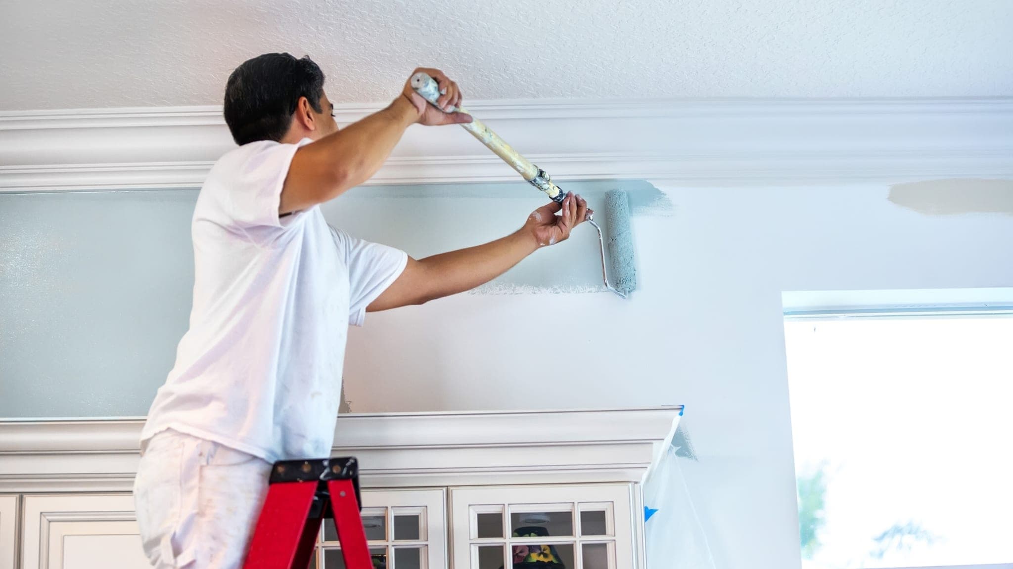 Pintor profesional aplicando pintura en el interior de una vivienda
